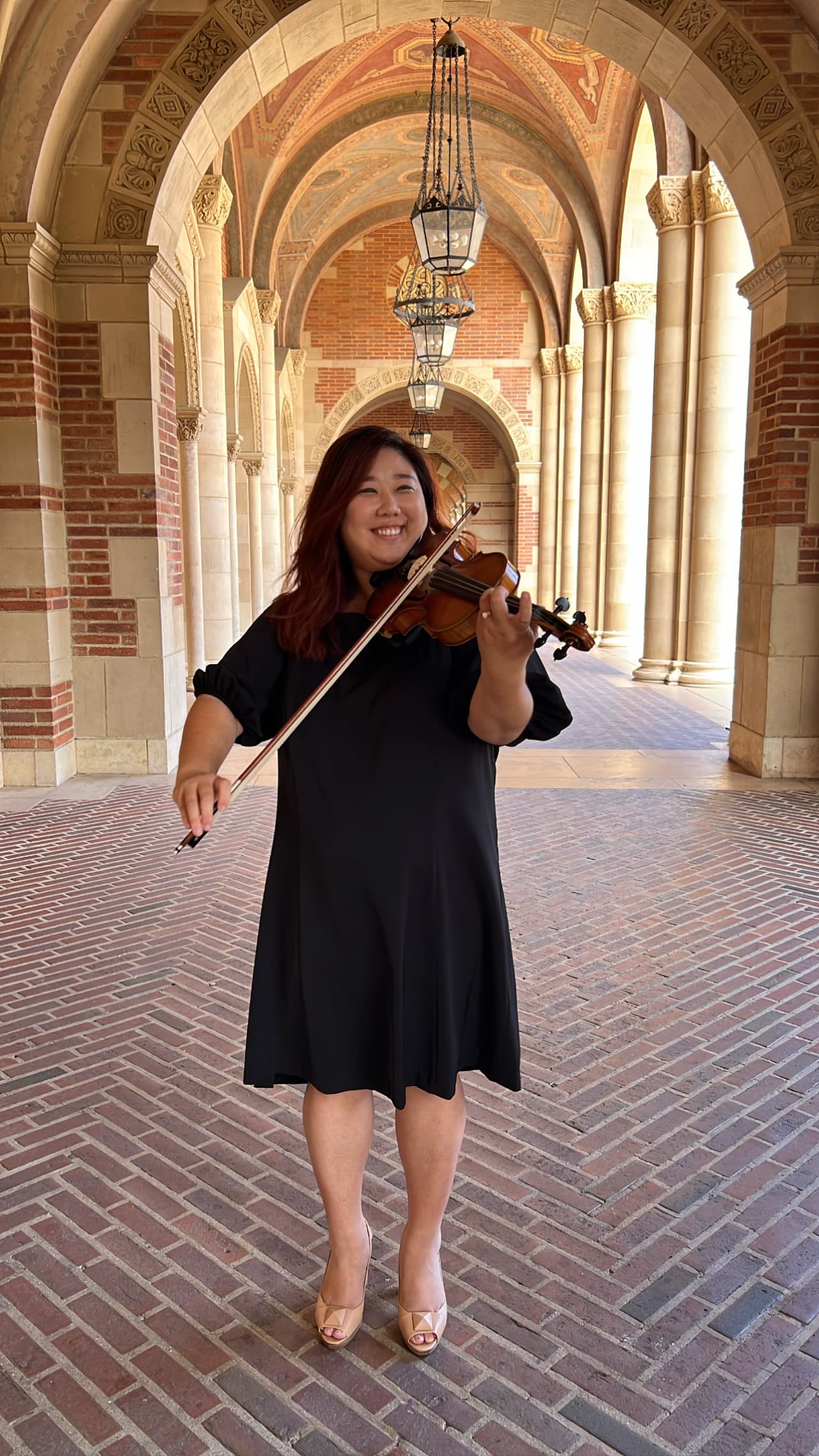 Fay You playing violin in an ornate stone archway
